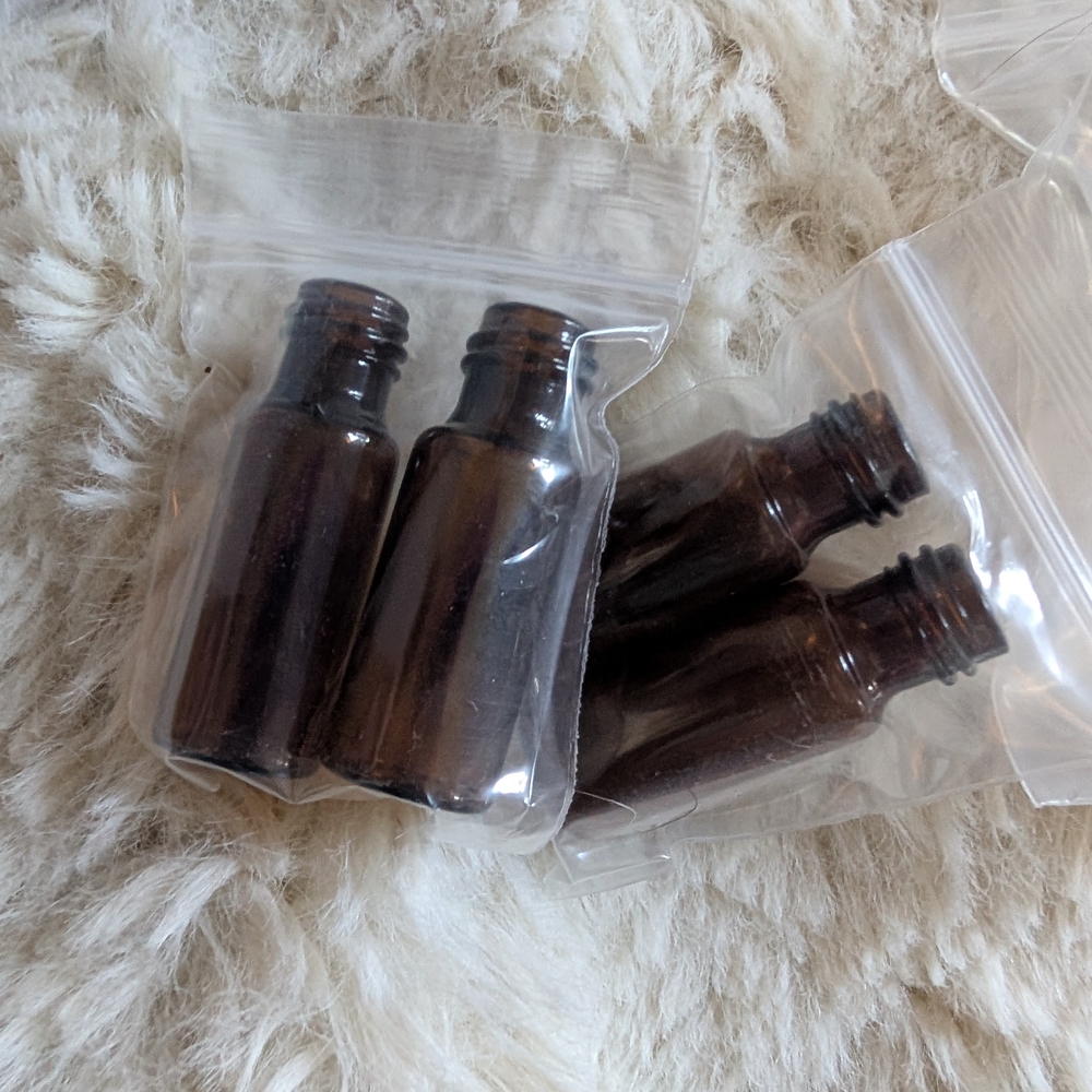 Assortment Of Clear And Amber Glass Rollerball And Spray Bottles.